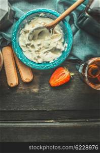 Creme for tiramisu making. Mascarpone cheese with Italian amaretto liqueur in blue bowl on dark rustic wooden background, top view, place for text. Italian food concept