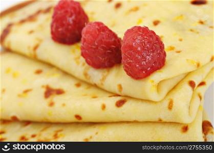 Crepe on a plate with a raspberry. A detailed photo fried thin pancake.