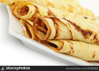 Crepe roll up a tubule on a plate. It is isolated on a white background.
