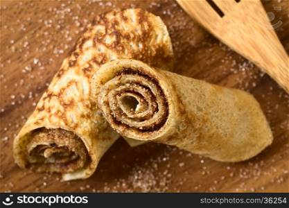 Crepe rolls filled with cinnamon and sugar, photographed overhead on wood with natural light (Selective Focus, Focus in the middle of the image)