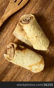 Crepe rolls filled with cinnamon and sugar, photographed overhead on wood with natural light (Selective Focus, Focus on the top of the rolls)
