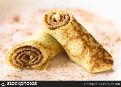 Crepe rolls filled with cinnamon and sugar, photographed with natural light (Selective Focus, Focus on the front of the right roll)
