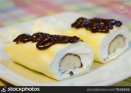 crepe rolls filled with white cream and banana, topping with chocolate syrup