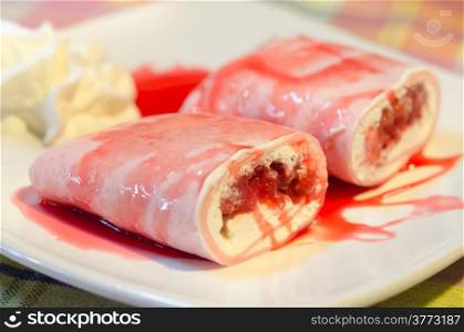 crepe rolls filled with white cream and strawberry, topping with strawberry syrup