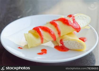 crepe rolls filled with white cream , topping with strawberry sauce