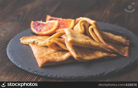 Crepes Suzette with slices of blood orange on the black stone board