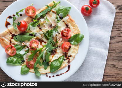 Crepes with cherry tomatoes, italian cheese and arugula on the plate