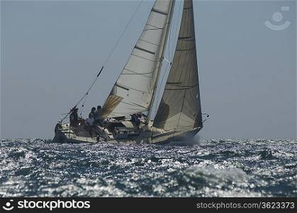 Crew members on board yacht competing in team sailing event California