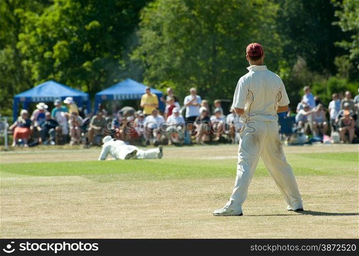 cricket fielder watching as his team-mate drops a catch