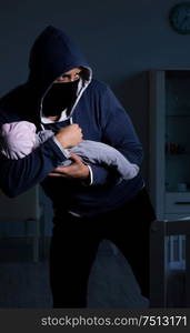 Criminal stealing baby in human child traficking concept. The criminal stealing baby in human child traficking concept