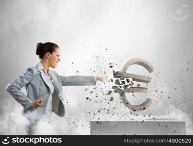 Crisis concept. Image of businesswoman crashing stone euro symbol