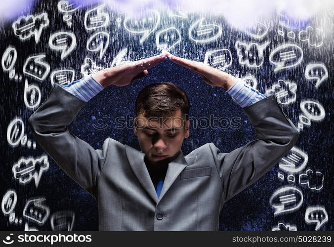 Crisis in business. Young businessman under rain covering head with hands