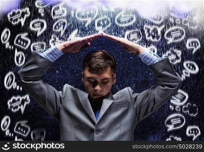 Crisis in business. Young businessman under rain covering head with hands