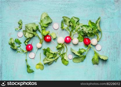 Crisp white and red radishes with leaves on light blue wooden background, top view