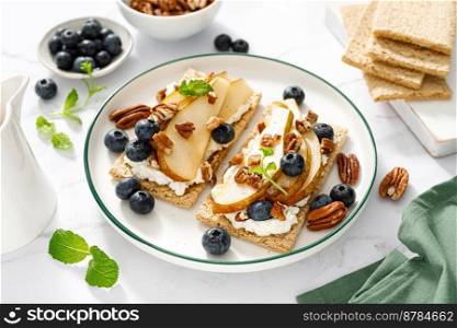 Crispbread with cream cheese, sweet pears, blueberry and pecan nuts. Top view