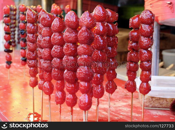 Crispy candied strawberries on a stick at street food market in Taiwan.