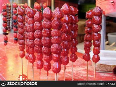 Crispy candied strawberries on a stick at street food market in Taiwan.