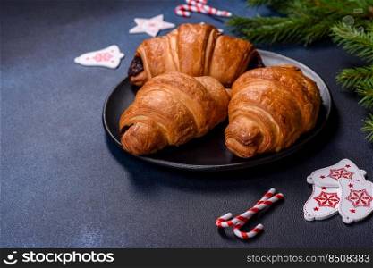 Crispy chocolate croissant with Christmas decorations on wooden cutting board on dark concrete background. Crispy chocolate croissant with Christmas decorations on wooden cutting board