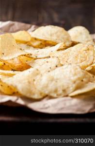 Crispy delicious pepper potato crisps chips snack on dark wooden board and brown paper