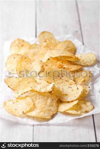 Crispy delicious pepper potato crisps chips snack on white wooden and paper