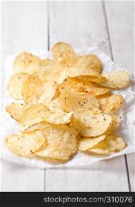 Crispy delicious pepper potato crisps chips snack on white wooden and paper