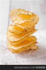 Crispy delicious pepper potato crisps chips snack on white wooden board