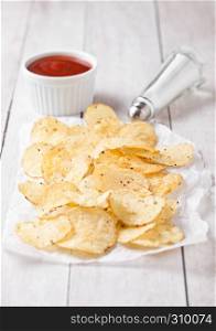Crispy delicious pepper potato crisps chips snack on white wooden board with sauce and salt