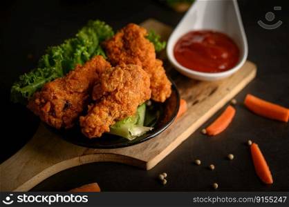 Crispy fried chicken on a cutting board with tomato sauce and carrot, Selective focus.