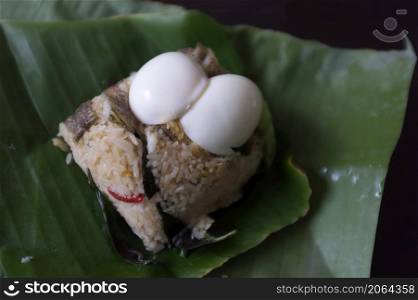 Crispy Gourami Fish and herb fried rice with boil egg on banana leaf