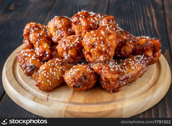 Crispy orange glazed chicken wings on the wooden board