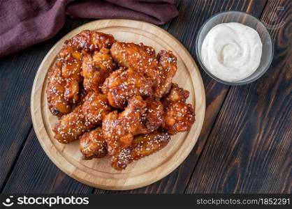 Crispy orange glazed chicken wings with blue cheese sauce on the wooden board