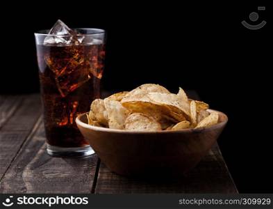 Crispy pepper crisps in wooden bowl with cola soda on wooden background