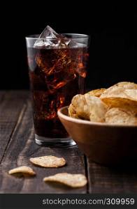 Crispy pepper crisps in wooden bowl with cola soda on wooden background