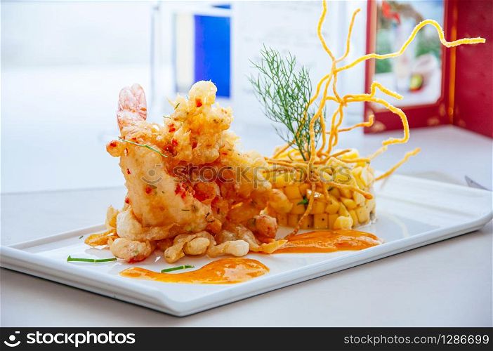 Crispy spicy deep fried tiger prawn with mango salsa and hot chilli thousand island sauce on white plate