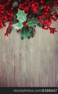 Cristmas Holly berry and fir twigs on the gray. Holly and fir twigs on wood wall