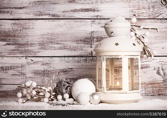 Cristmas lantern with decorations and snow over white shabby wooden background