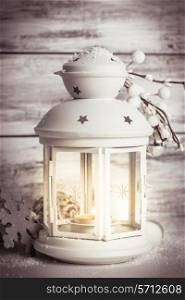 Cristmas lantern with decorations and snow over white shabby wooden background