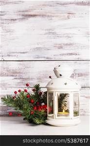 Cristmas lantern with fir and berries over shabby wooden background