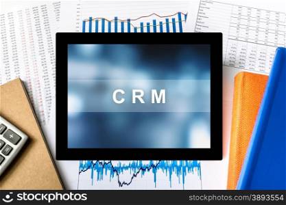 CRM or Customer relationship management word on tablet with financial graph background