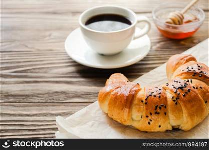 croissant, a Cup of instant coffee and honey on a textured wooden background top view, cozy and delicious Breakfast. Rustic background.. croissant, a cup of instant coffee and honey on a textured wooden background top view, cozy and delicious breakfast. Rustic background