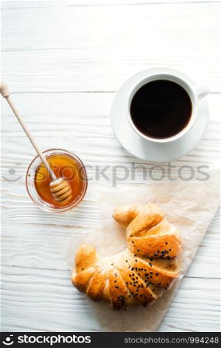 croissant, a cup of instant coffee and honey on a white textured wooden background top view, cozy and delicious breakfast. Rustic background.. croissant, a cup of instant coffee and honey on a white textured wooden background top view, cozy and delicious breakfast. Rustic background