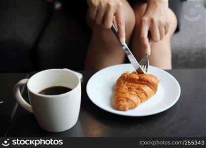 croissant and coffee with girl hand to eating in coffee shop