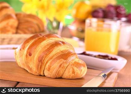 Croissant, jam, fruits and orange juice for breakfast (Selective Focus, Focus on the front of the croissant)