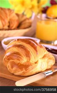 Croissant, jam, fruits and orange juice for breakfast (Selective Focus, Focus one third into the croissant)