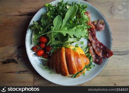 croissant with egg and bacon on wood background