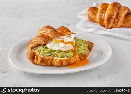 Croissant with guacamole and poached egg on the serving plate