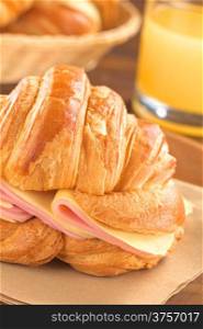 Croissant with ham and cheese (Selective Focus, Focus on the ham and cheese slices on the right and on the front of the croissant)