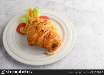 Croissant with hotdog on white dish decorate with tomato sliced and lettuce beautifully, copy space