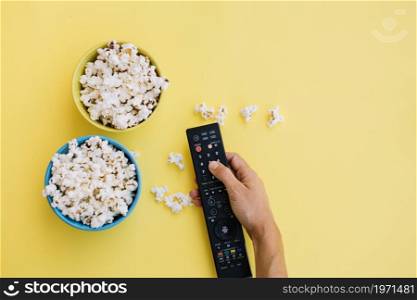 crop hand remote control near popcorn. High resolution photo. crop hand remote control near popcorn. High quality photo