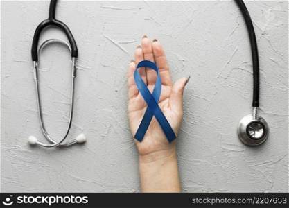 crop hand with blue ribbon near stethoscope